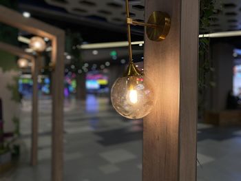 Close-up of illuminated light bulb hanging on ceiling