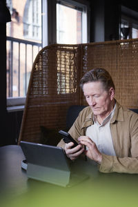 Senior man using phone and tablet