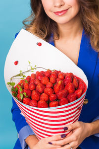 Midsection of woman holding strawberries in bowl