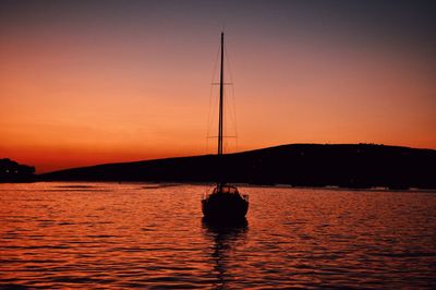 Silhouette sailboat in sea against sky during sunset