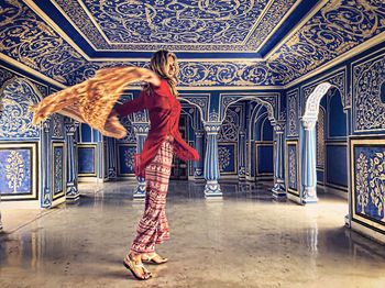 Full length of happy mature woman wearing traditional clothing spinning in palace