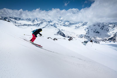 Woman skier skiing downhill in high mountains against mountains and clouds.