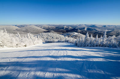 Scenic view of snow covered mountains against clear blue sky