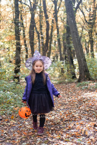 Halloween. cute little girl in witch costume with jack o lantern having fun outdoor