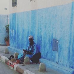 Man sitting against blue wall
