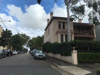 Cars on street by buildings against sky