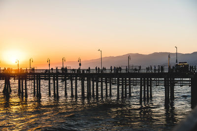 Silhouette pier over sea against sky during sunset