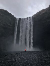 Scenic view of waterfall against cloudy sky