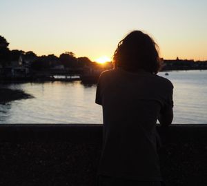 Silhouette of people standing by sea during sunset