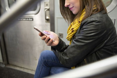 Midsection of woman using mobile phone while traveling in train