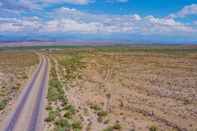 Scenic view of road amidst field against sky