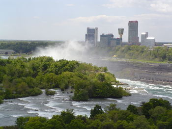 Scenic view of river by buildings against sky