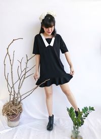 Full length portrait of woman standing against wall