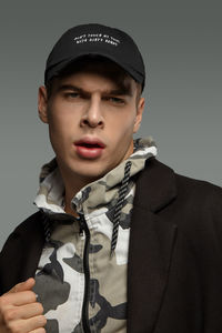 Portrait of young man standing against gray background