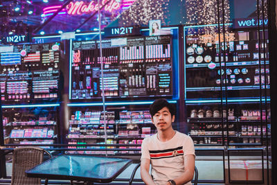 Portrait of smiling young man sitting at sidewalk cafe