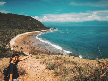 Portrait of teenage girl standing at beach against sky