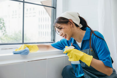 Side view of young woman washing hands in bathroom