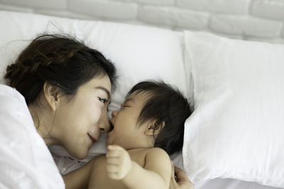 Playful mother and daughter on bed at home