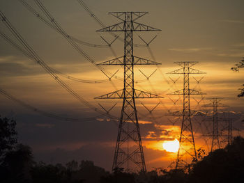 Low angle view of silhouette electricity pylon against sky during sunset