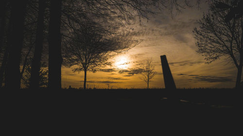 Silhouette trees on landscape against sky during sunset