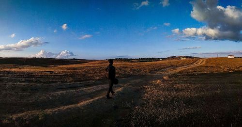 Woman walking on field against sky