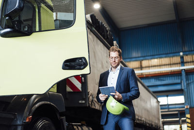 Male manager using digital tablet while standing by truck