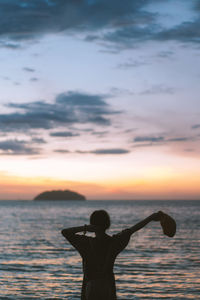 Silhouette person standing by sea against sky during sunset