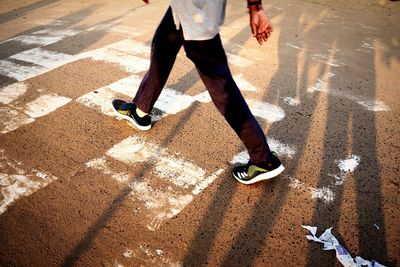 Low section of man with shadow on street