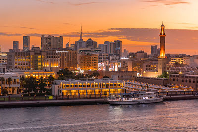 Illuminated buildings in city at sunset