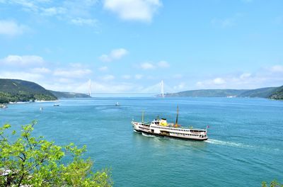 Bridge and ferry over the sea against the sky