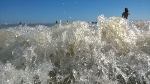 People standing in sea against clear sky