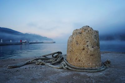 Rope tied to bollard on sea against sky