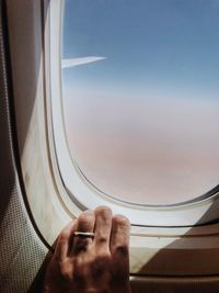 Cropped image of hand on airplane window