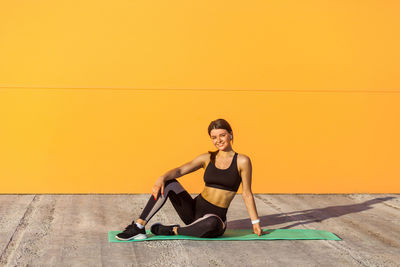 Portrait of woman smiling against yellow wall