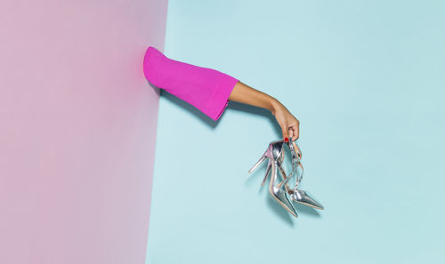 High angle view of hand holding umbrella against blue wall