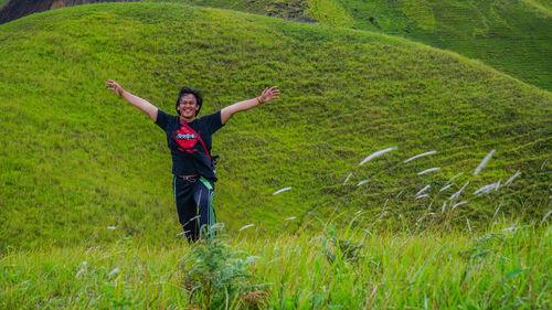 Full length portrait of a smiling young man lying on grassy field