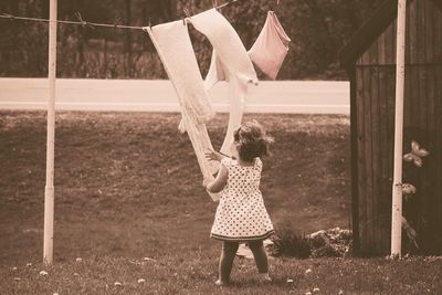 Girl holding fabric hanging on clothesline in yard