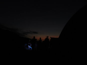 Silhouette people standing against sky at dusk