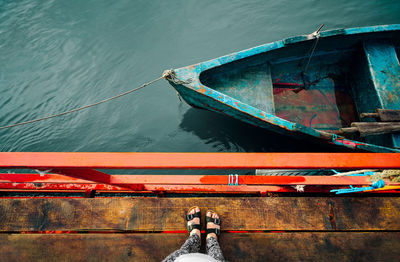 Person on wooden pier by fishing boat