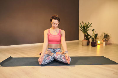 Young woman doing yoga on yoga mat in atmospheric yoga studio