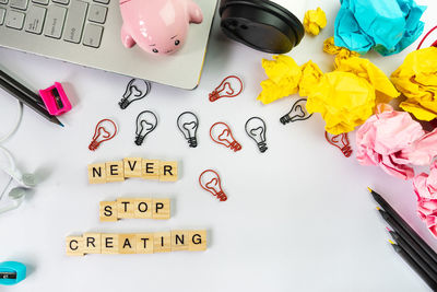 Directly above shot of text by light bulbs and office supplies on table