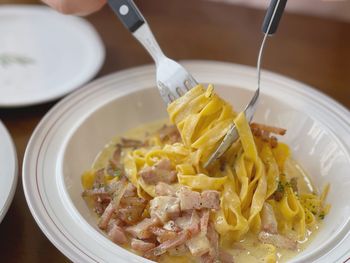 Close-up of pasta in bowl on table rolling with fork