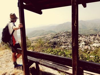 Side view of man standing on mountain against sky