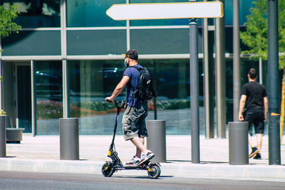 Rear view of man riding bicycle on street