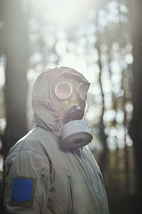 Close-up of man wearing protective suit against trees in forest