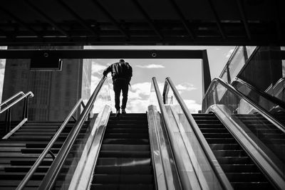 Rear view of man walking on escalator in building