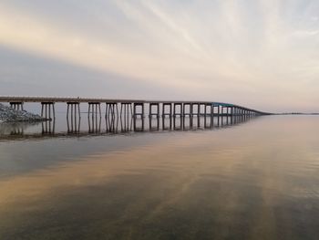 Pier over sea against sky during sunset