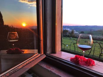 Restaurant by glass window against sky during sunset