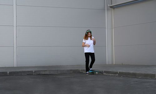 Full length of young woman standing against wall