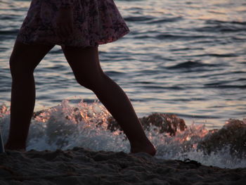 Low section of woman on rock at beach